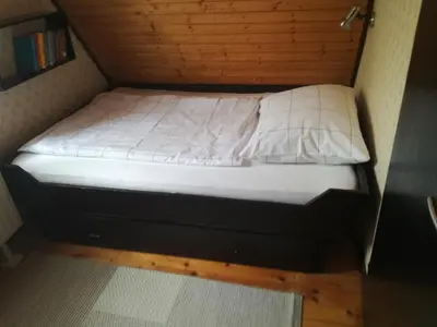 a small bed in a small room with white sheets at Hugo's House in Rakitna