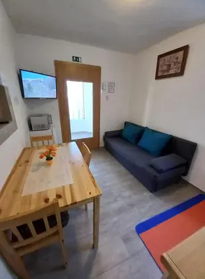 a living room with a wooden table and a blue couch at Apartmaji SLATENIK in Bovec