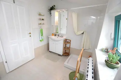 a white bathroom with a sink and a mirror at Vila Salamander in Štanjel