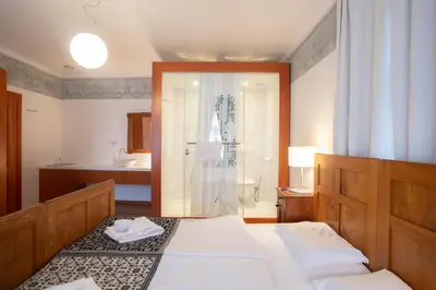 a bedroom with two beds and a bathroom with a shower at Pr'Gavedarjo Eco Heritage B&B in Kranjska Gora