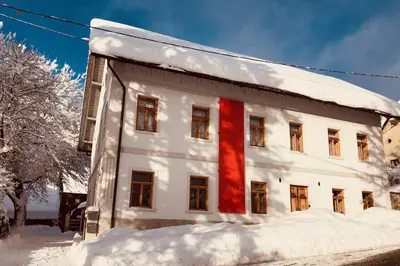a building covered in snow with a red stripe on it at Pr'Gavedarjo Eco Heritage B&B in Kranjska Gora