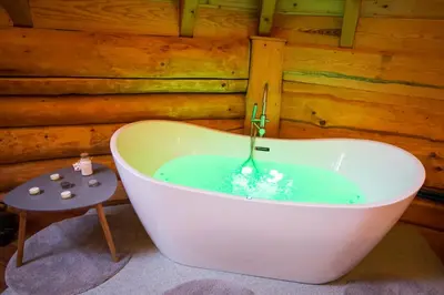 a bath tub filled with blue water in a room at Wellness hiska Izabela in Križevci pri Ljutomeru