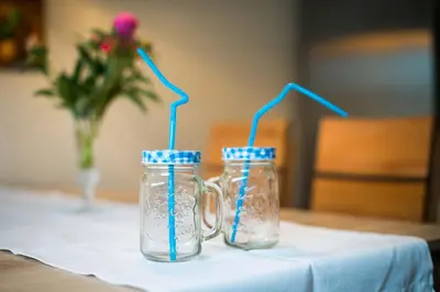two mason jars with blue drinking straws sitting on a table at Apartma Ela in Bled