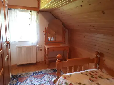 a bedroom in a log cabin with a bed and a window at Holiday House Jasna in Kranjska Gora