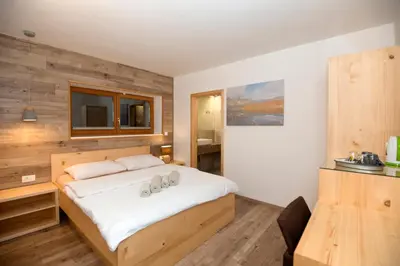 a bedroom with a large white bed with a wooden wall at Vila Alpina in Bled