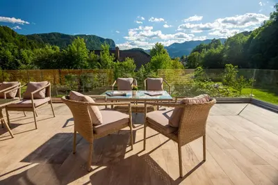 a patio with a glass table and chairs on a deck at Vila Alpina in Bled