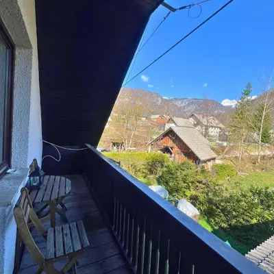 a balcony with a bench and a view of a house at Apartments Korošec Breda in Bohinj