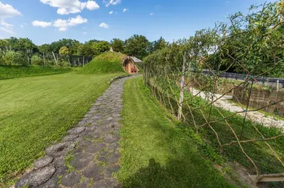 a path through a field with a thatch roof at Apartma Zemljanka in Ljutomer