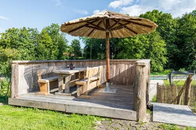 a wooden table and an umbrella on a wooden deck at Apartma Zemljanka in Ljutomer