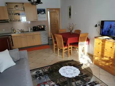a living room with a table and a kitchen at Apartma Slavc in Kranjska Gora