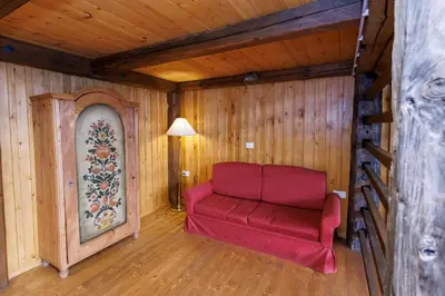 a red couch in a room with wooden walls at House Budkovič in Bohinj