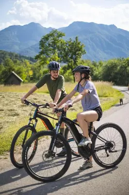 a man and a woman riding bikes down a road at House Budkovič in Bohinj