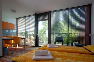 a bedroom with a large bed and large windows at Hostel Pekarna in Maribor