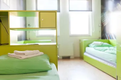 a room with two green beds and a mirror at Hostel Pekarna in Maribor