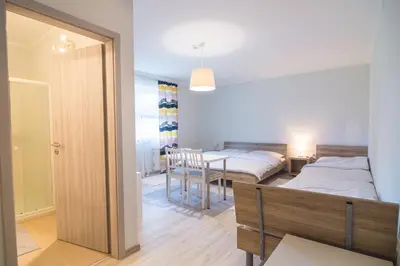 a bedroom with two beds and a table and a dining room at HOP HOUSE Garni Hotel in Postojna
