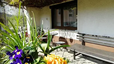 a porch with a bench and flowers in front of a building at Nauportus in Vrhnika