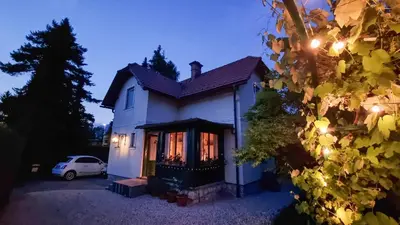 a white house with a car parked in the driveway at Moja Vila Bled in Bled