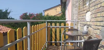a yellow fence with a table on a balcony at Relax in Črni Kal 2 in Črni Kal