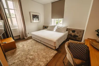 a bedroom with a bed and a table and a chair at Gredič Heritage Residences in Dobrovo