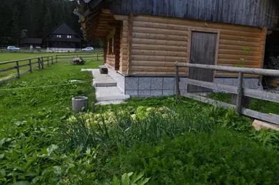 a log cabin with a porch and a fence at POČITNIŠKA HIŠA JURČEK POKLJUKA in Goreljek