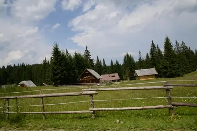 a wooden fence in a field next to a house at POČITNIŠKA HIŠA JURČEK POKLJUKA in Goreljek