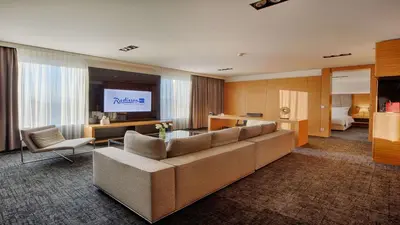 a living room with a couch and a flat screen tv at Radisson Blu Plaza Hotel Ljubljana in Ljubljana