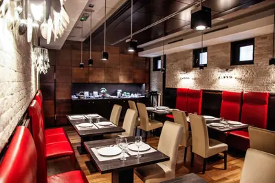 a restaurant with tables and chairs and red booths at Hotel Lent in Maribor