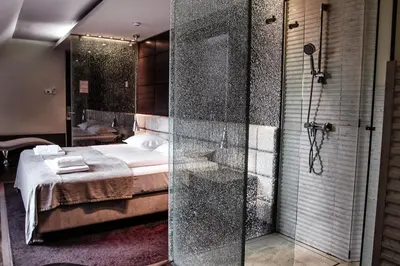 a bathroom with a shower and a bed in a room at Hotel Lent in Maribor