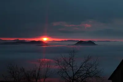 a sunset over a fog covered mountain range at Apartma pri Boštjanu in Škofja Loka