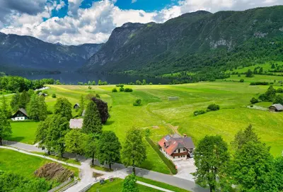an aerial view of a house in a field with mountains at Apartments Kovačič in Bohinj