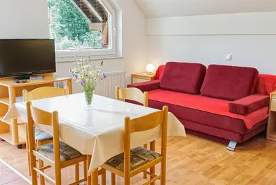 a living room with a red couch and a table at Apartments Kovačič in Bohinj