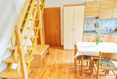 a kitchen and dining room with a wooden ladder and a table at Apartments Kovačič in Bohinj