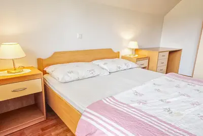 a bedroom with a bed and two night stands and two lamps at Apartments Kovačič in Bohinj