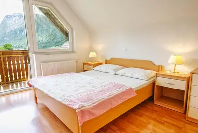 a bedroom with a bed and a large window at Apartments Kovačič in Bohinj