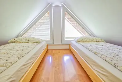 two beds in a room with two windows at Apartments Kovačič in Bohinj