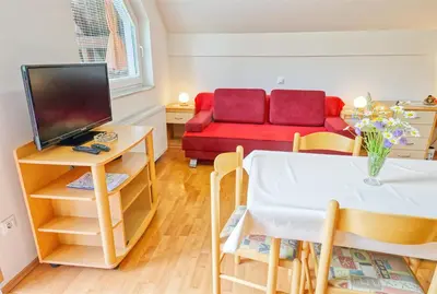 a living room with a table and a red couch at Apartments Kovačič in Bohinj