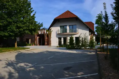 a white house with a balcony and a driveway at Hotel Rakar in Trebnje