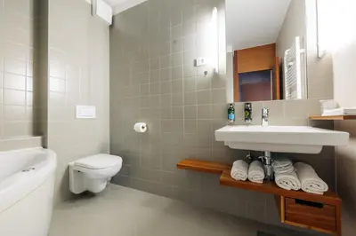 a white bathroom with a sink and a toilet at Hotel Rakar in Trebnje
