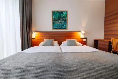 a hotel room with two beds and a desk at Hotel Rakar in Trebnje
