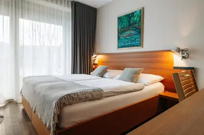 a bedroom with a large bed with a wooden headboard at Hotel Rakar in Trebnje