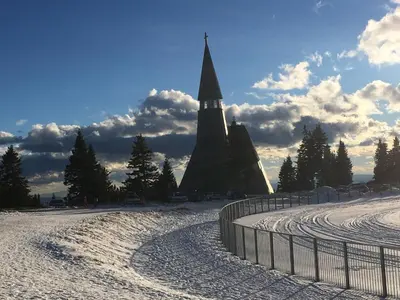 a church steeple in the snow next to a fence at Apartma Rogla - Gaber 98 in Resnik