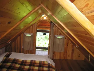 a bed in the attic of a wooden cabin at Holiday Home Carovina in Paradiž