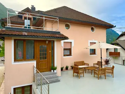 a house with a patio with chairs and an umbrella at Apartma Kemper in Bovec