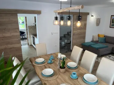 a dining room and living room with a wooden table and chairs at Apartma Kemper in Bovec