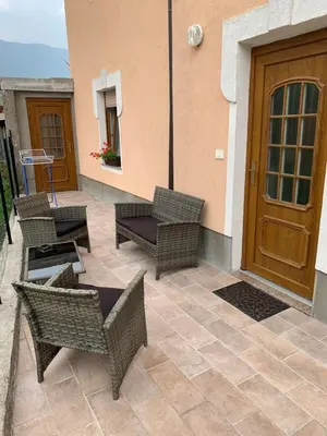 a patio with wicker chairs and a wooden door at Apartma Kemper in Bovec