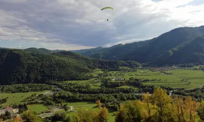a paraglider flying over a valley in the mountains at Apartma Mika in Most na Soči
