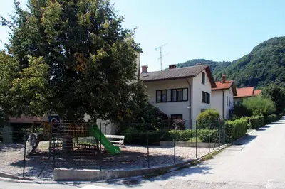 a playground with a green slide in front of a house at Apartma Mika in Most na Soči