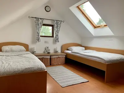 two beds in a attic bedroom with a window at Apartma Pr'Toman in Kamna Gorica