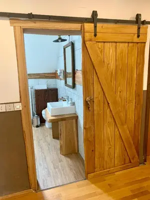 a bathroom with a wooden door and a sink at Apartma Pr'Toman in Kamna Gorica