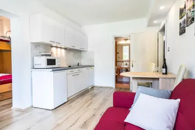 a living room with a red couch and a kitchen at Apartment Japka in Bovec